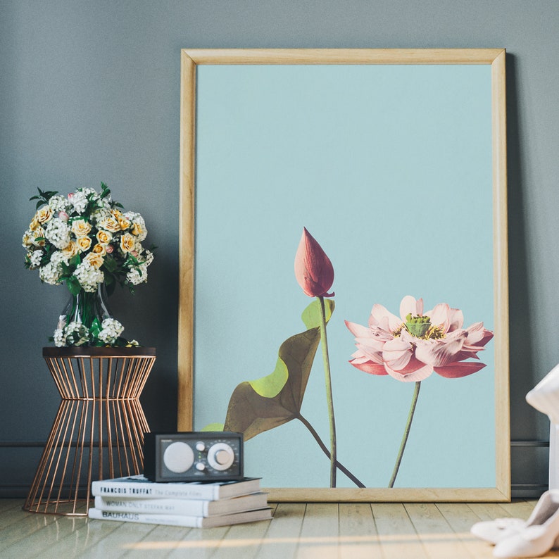May include: A framed print of a pink and white lotus flower with green leaves on a light blue background.