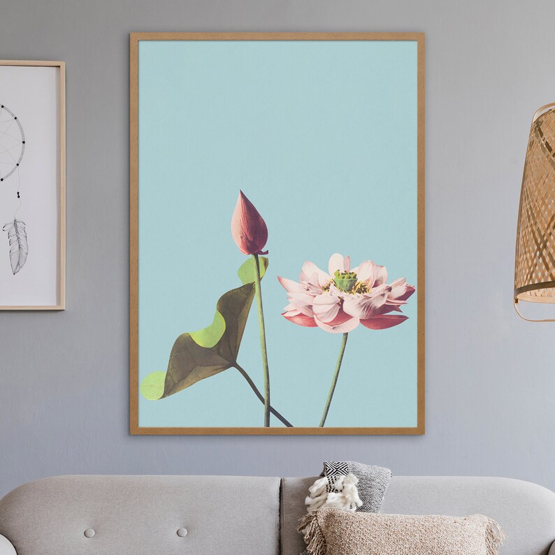 May include: A framed print of a pink lotus flower with a green leaf and a closed bud on a light blue background.