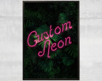 Op de afbeelding: Een ingelijst print met een roze neon-bord met de tekst "Custom Neon" tegen een donkergroene, bladerrijke achtergrond.