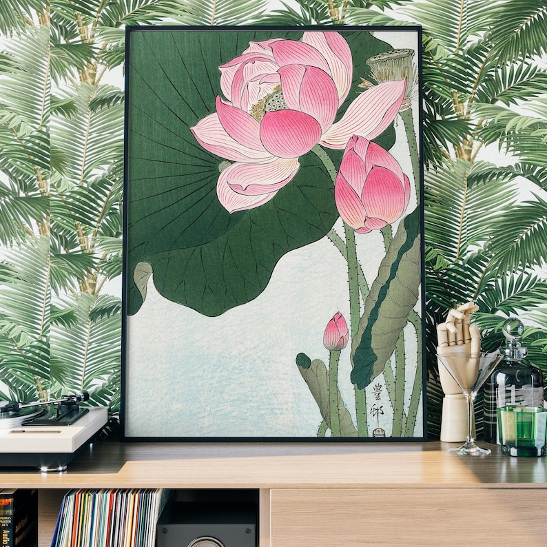 May include: A framed print of a Japanese-style painting featuring pink lotus flowers and green leaves. The painting is set against a light blue background and includes Japanese text in the bottom right corner.