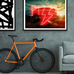 May include: A framed print with a photo of the Colosseum in Rome, Italy. The word "PIZZA" is written in neon pink letters with a lightning bolt symbol in the center. The sky is a vibrant orange and yellow.