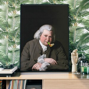 May include: A framed portrait of a man in a dark suit and white cravat, holding a green and yellow party blower in his mouth. The background is a dark brown.