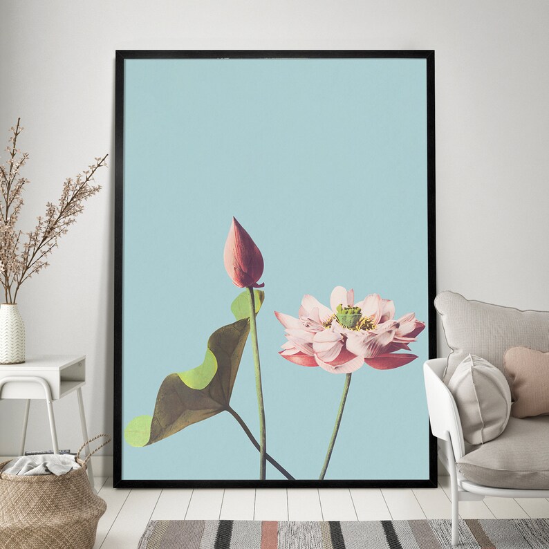 May include: A framed print of a pink and white lotus flower with a green leaf and a pink bud against a light blue background.