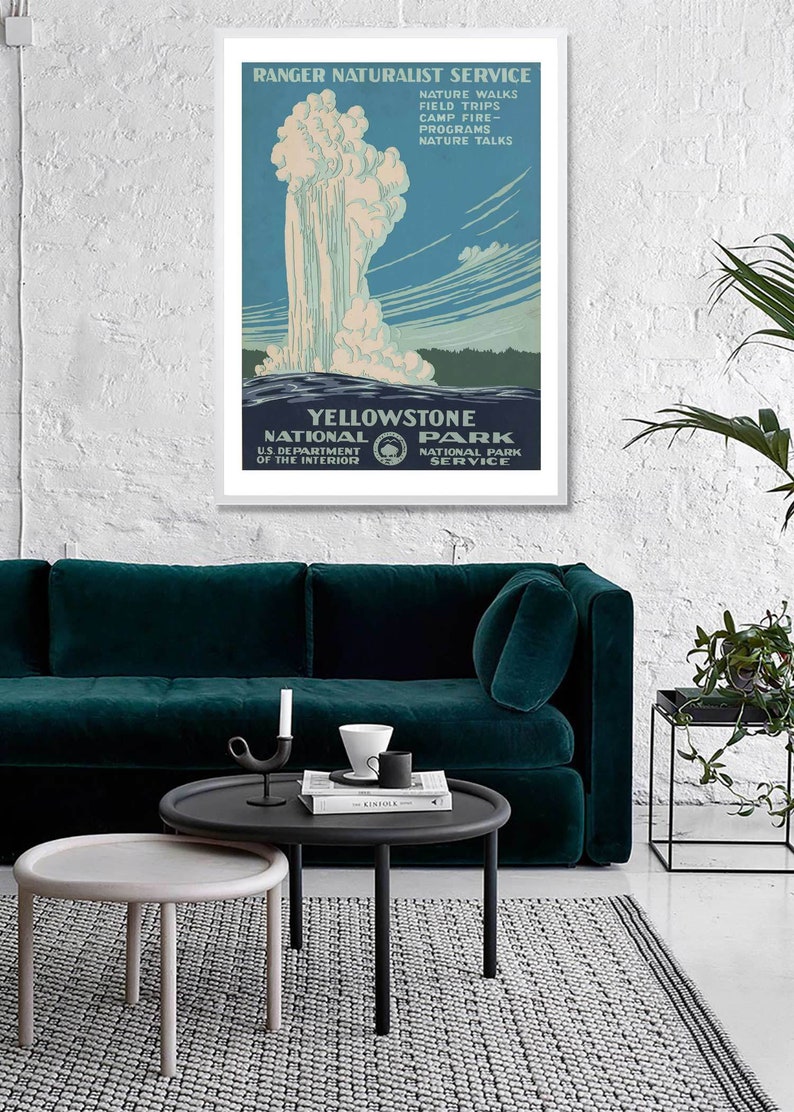 May include: A vintage travel poster for Yellowstone National Park, featuring a geyser erupting against a blue sky with white clouds. The poster is framed in white and has text that reads "Ranger Naturalist Service" and "Yellowstone National Park".