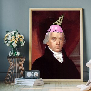 May include: A framed portrait of a man with a pink ice cream cone on his head. The man is wearing a black suit and white shirt. The background is a red curtain.