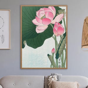 May include: A vintage Japanese woodblock print of pink lotus flowers with green leaves. The print is framed in a light wood frame.