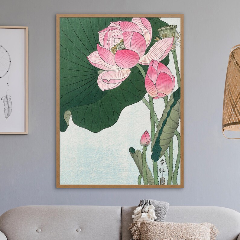 May include: A vintage Japanese woodblock print of pink lotus flowers with green leaves. The print is framed in a light wood frame.