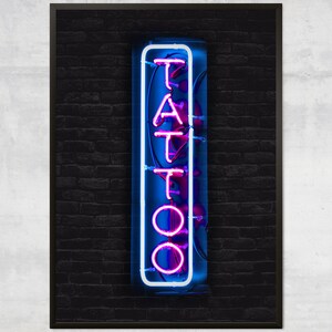 May include: A neon sign with the word "TATTOO" in white letters with a pink outline against a dark brick wall background.