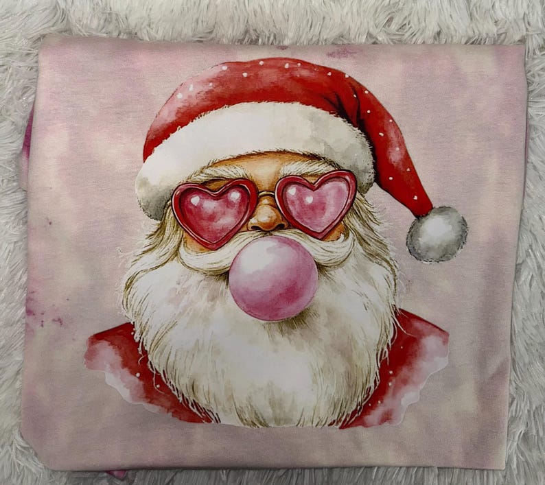 May include: A pink graphic featuring Santa Claus wearing heart-shaped sunglasses and blowing a bubble. Santa's red hat and suit contrast with his white beard and the pink bubblegum. The design is on a pink background.