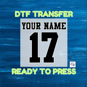 May include: A white and blue DTF transfer with the text "YOUR NAME" and the number "17" in black. The text "DTF TRANSFER" and "READY TO PRESS" are in green.