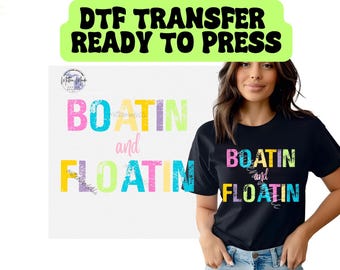 May include: A black t-shirt with the words "BOATIN and FLOATIN" in colorful, distressed lettering. The image also includes the text "DTF TRANSFER READY TO PRESS" in a green banner.