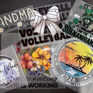 May include: A collection of heat transfer vinyl designs. Designs include the word "Grandma" with names, a volleyball bow, a raccoon with a beer, floral arrangements, and a Caribbean sunset scene. The designs are in various colors and fonts.