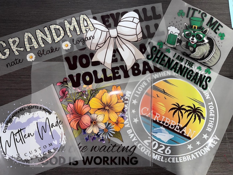 May include: A collection of heat transfer vinyl designs. Designs include the word "Grandma" with names, a volleyball bow, a raccoon with a beer, floral arrangements, and a Caribbean sunset scene. The designs are in various colors and fonts.