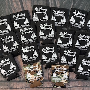 May include: A collection of black can coolers with the text "In Loving Memory" and the name "RONALD KRYCH JR" printed in white. The coolers also feature a tree graphic and dates.