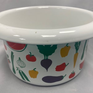 Puede incluir: Tazón de esmalte blanco con estampado de verduras de colores. El tazón presenta una variedad de verduras, incluyendo zanahorias, pimientos, cebollas y berenjenas.