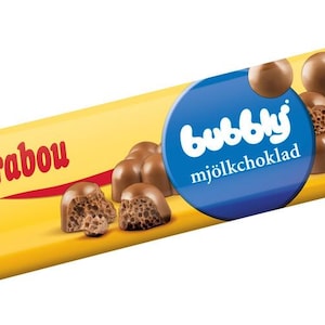 Può includere: Un involucro di cioccolato giallo con le parole "Marabou" e "bubbly mjölkchoklad" stampate su di esso. L'involucro presenta un cerchio blu con la parola "bubbly" in lettere bianche. La barretta di cioccolato è ripiena di cioccolato al latte e ha una consistenza spumosa.