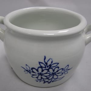 Könnte beinhalten: Weiße Keramik-Topf mit zwei Griffen und einem blauen Blumendesign.