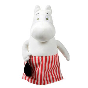 Op de afbeelding: Een wit pluche karakter met een grote snuit, groene ogen en een rood-wit gestreepte schort. Het personage houdt een zwart voorwerp vast. Het speelgoed heeft een grillig ontwerp.