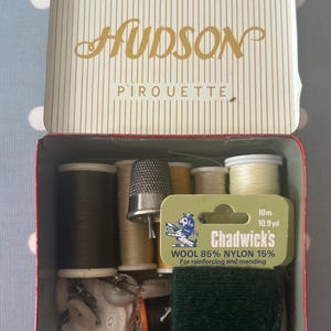 May include: A vintage sewing kit in a red and white tin box with the words "Hudson Pirouette" on the lid. The kit contains spools of thread in various colors, a thimble, and a small piece of lace.