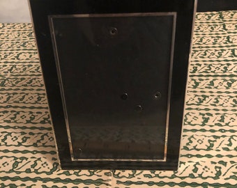 May include: A black picture frame with a silver border. The frame is about 5 inches tall.