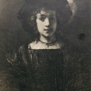 May include: A black and white portrait of a young woman wearing a dark hat with a white trim. She is wearing a dark dress with a white collar and a pearl necklace.