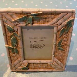 Puede incluir: Marco de fotos decorativo beige con diseño de bambú y hojas verdes. El marco tiene las palabras "REJOICEFUL SINGING" y un mensaje manuscrito. Ideal para una foto.