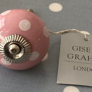 Puede incluir: Pomo de cerámica rosa con lunares blancos y base de metal plateado. El pomo tiene una etiqueta que dice "Gisela Graham London".