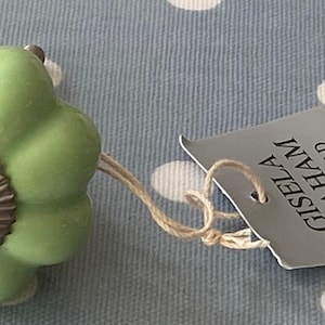 Puede incluir: Un pomo de cerámica verde claro con un centro de metal plateado y un borde festoneado. El pomo está unido a una cuerda y una etiqueta que dice "Gisela Graham Limited".