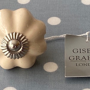 May include: A cream-colored ceramic pumpkin-shaped knob with a silver metal center. The knob is attached to a white string and a tag that reads "Gisela Graham London".