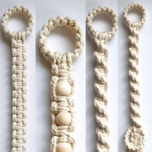 May include: A macrame rope and wooden bead necklace with a circular loop at the top. The necklace is made with a white cotton rope and features three wooden beads.