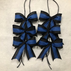 May include: Six blue and black striped bows with long tails. The bows are tied together and are ready to be used as decorations.