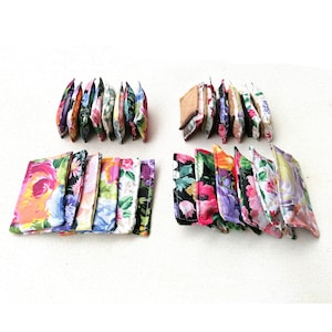 May include: Two rows of colorful floral fabric pouches, each with a different pattern. The pouches are arranged in a staggered pattern, with the top row slightly offset from the bottom row. The pouches are all made of a soft, cotton fabric and have a zipper closure.