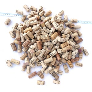 May include: A large pile of used wine corks, many with different brand names and logos printed on them. The corks are mostly brown and beige in color.