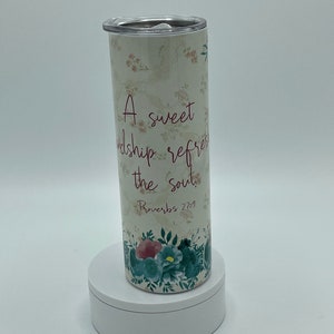 May include: A white stainless steel tumbler with a floral design and the quote "A sweet friendship refreshes the soul. Proverbs 27:9"