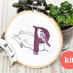 May include: A purple and gray embroidery kit featuring a pelican with the letter "P" in the center. The embroidery is in a wooden hoop.