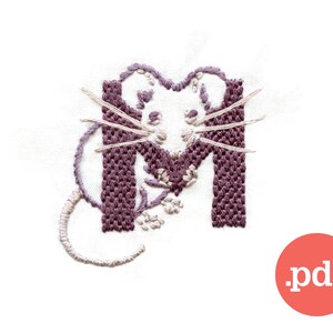 Può includere: Lettera M ricamata con un design a forma di topo. Il topo è bianco con orecchie rosa e un naso rosa. La lettera M è viola e la coda del topo è bianca.