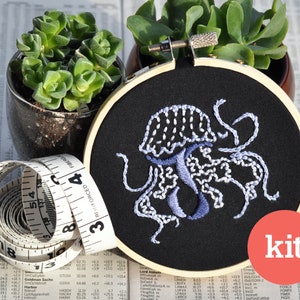 May include: A DIY embroidery kit featuring a blue and white jellyfish design on black fabric. The kit includes a hoop, needle, and thread. The word "kit" is printed in white on a red circle.