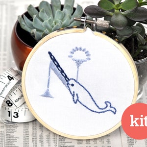 May include: Embroidery kit featuring a blue narwhal with a fishing rod and a dandelion. The kit includes all the materials needed to complete the embroidery project. The embroidery hoop is made of wood and has a diameter of 6 inches.