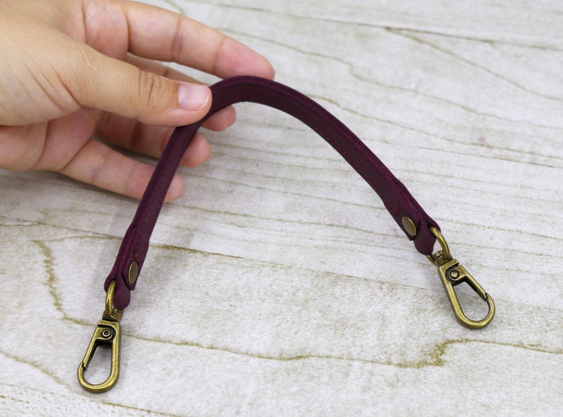 May include: A burgundy leather strap with two gold metal clasps. The strap is about 10 inches long.