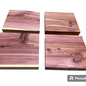 May include: Four pieces of natural wood, each with a unique grain pattern. The wood is a reddish-purple color and has a smooth, polished finish.