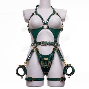 May include: A green leather harness with gold accents and buckles. The harness includes a chest piece, a waist belt, thigh straps, and wrist cuffs.