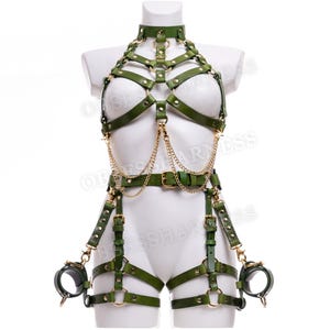 May include: A green leather harness with gold hardware and chains. The harness includes a chest piece, a waist belt, and leg straps. The harness also includes a pair of handcuffs.