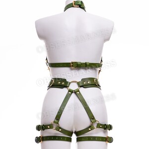 May include: Green leather harness with gold hardware. The harness includes a choker, a chest piece, a waist belt, and thigh straps.
