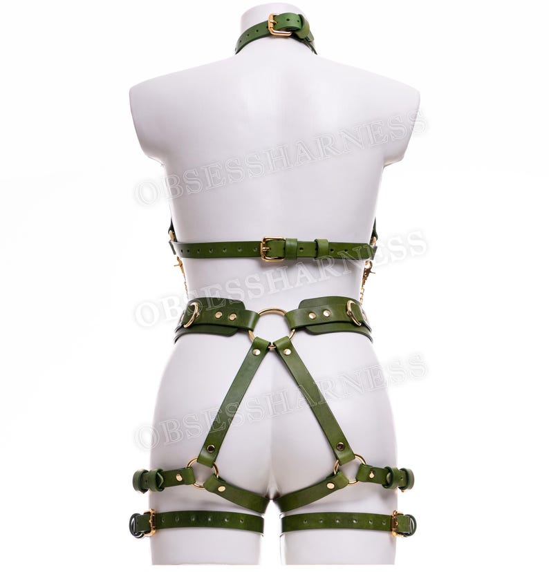 May include: Green leather harness with gold hardware. The harness includes a choker, a chest piece, a waist belt, and thigh straps.