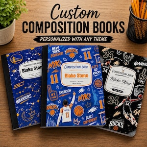 May include: Three custom composition books with personalized covers featuring basketball themes. The left book is blue and gold with Warriors branding. The center book is blue and orange with Knicks graphics. The right book is black and white with Bucks imagery.