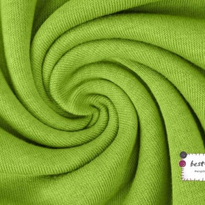 May include: A close-up of a bright green fabric with a textured surface. The fabric is folded and twisted, creating a swirling pattern.