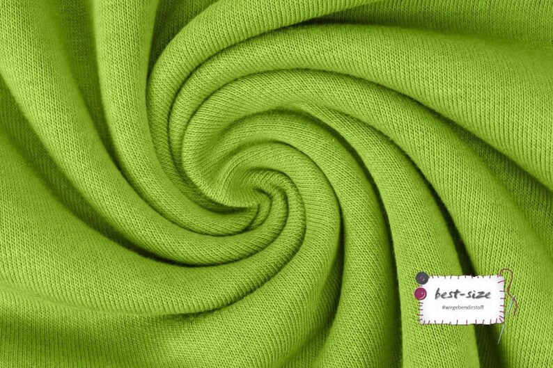 May include: A close-up of a bright green fabric with a textured surface. The fabric is folded and twisted, creating a swirling pattern.