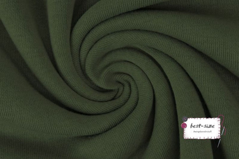May include: Close-up of a dark green fabric with a ribbed texture. The fabric is folded and twisted, creating a swirling pattern.