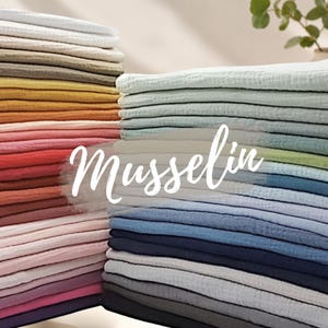 Könnte beinhalten: Gestapelte Stoffe aus farbenfrohem Musselin in verschiedenen Farbtönen, darunter Weiß, Grau, Gelb, Rosa, Rot, Blau und Grün. Das Wort "Musselin" ist in Schreibschrift über dem Bild geschrieben. Der Stoff wirkt weich und geschichtet.