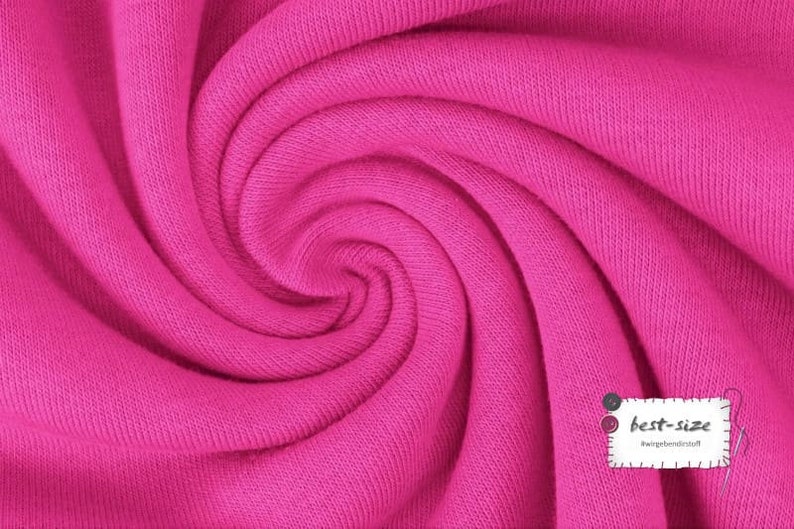 May include: Close-up of a bright pink fabric with a soft, textured surface. The fabric is folded and twisted, creating a swirling pattern.